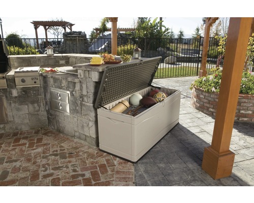 Coffre de rangement ouvert à l''extérieur, à côté d''une cuisine extérieure sur une terrasse, contenant du matériel de sport