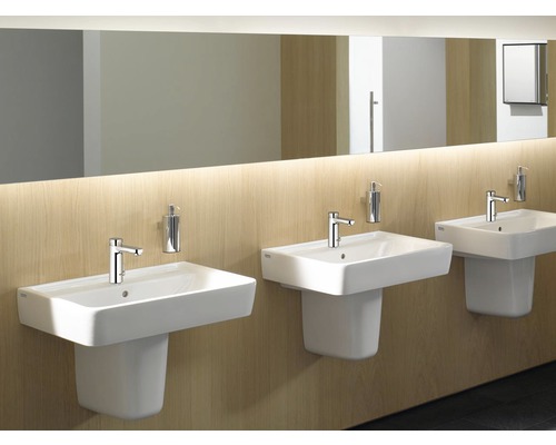 Drei weisse Waschbecken mit Armaturen und Seifenspendern in einem Badezimmer.