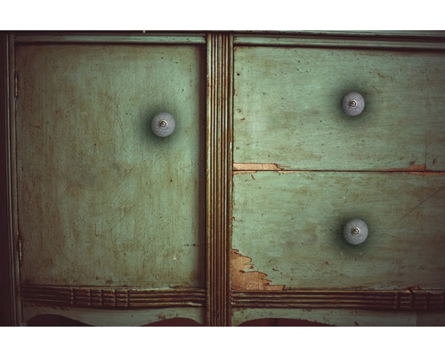 Detailansicht eines grünen Holzschranks mit drei Schubladen und runden Griffen