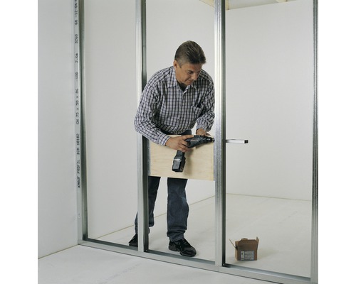 Un homme monte une cloison sèche avec une visseuse sans fil.