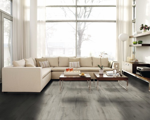 Helles Wohnzimmer mit Ecksofa, Couchtischen und grauem Holzboden