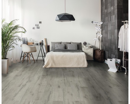 Schlafzimmer mit hellem Holzboden, Bett und Schreibtisch.