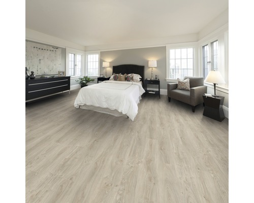 Heller, geräumiger Schlafraum mit Laminatboden, Bett, Kommode und Sessel.