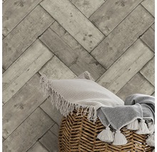Papier peint avec motif à chevrons en bois, coussin et couverture dans un panier