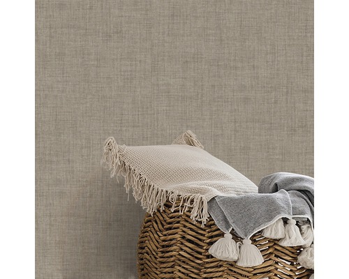 Coussin décoratif et couverture dans un panier devant un mur structuré