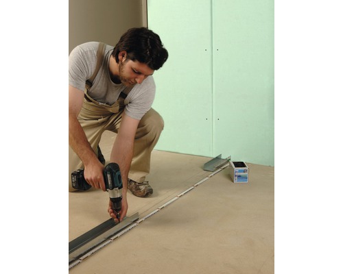 Handwerker befestigt Metallprofil mit Akku-Bohrschrauber an Boden