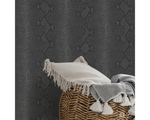 Tapete mit Reptilienmuster neben Kissen und Decke auf einem Hocker