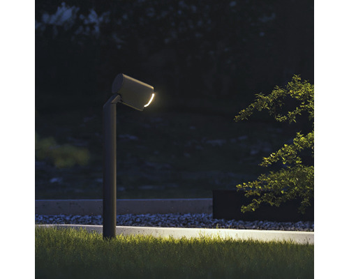 Scène de jardin avec une borne lumineuse ronde et grise en métal