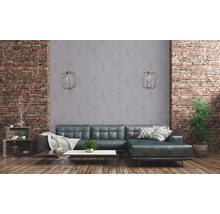 Wohnzimmer mit Ecksofa, Couchtisch und dekorativen Elementen vor einer Ziegelwand
