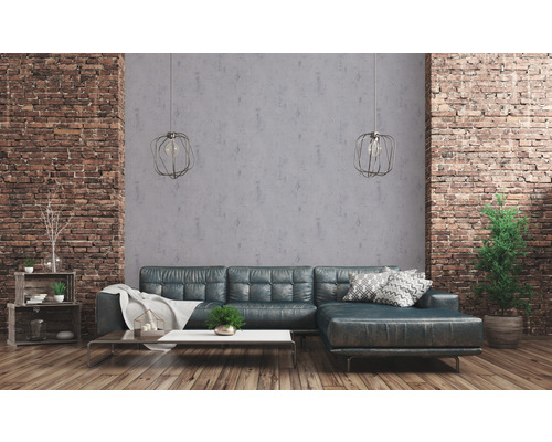 Wohnzimmer mit Ecksofa, Couchtisch und dekorativen Elementen vor einer Ziegelwand