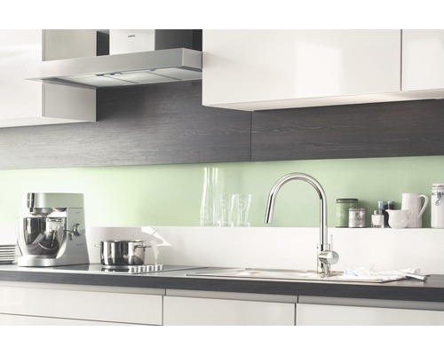 Küchenszene mit Küchenarmatur, Spüle, Kochfeld, Dunstabzugshaube und Küchengeräten.