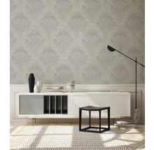 Dekoratives Wohnzimmer mit gemusterter Tapete, Sideboard, Hocker und Stehleuchte.