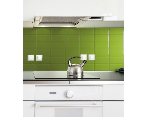 Küchenszene mit Herd, Kochfeld und Wasserkocher vor grüner Fliesenwand