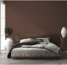 Schlafzimmer mit brauner gemusterter Tapete, Bett, Nachttisch und Zimmerpflanze