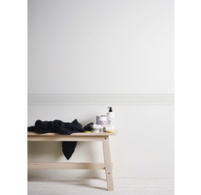 Mur clair avec bordure à méandres grecs et lavabo avec produits de soin