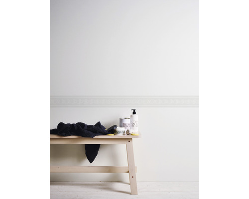 Mur clair avec bordure à méandres grecs et lavabo avec produits de soin