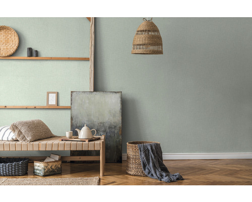 Wohnraum mit grüner Textiltapete, Holzregal und Flechtkorb