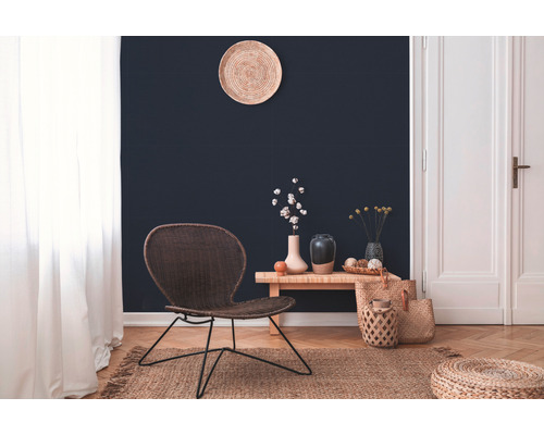 Wohnzimmer mit geflochtenem Stuhl, Holzbeistelltisch und dekorativen Accessoires auf einem Teppich