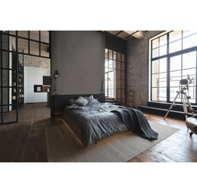 Innenaufnahme eines Schlafzimmers im Loft-Stil mit Bett, Fenstern und Holzboden.