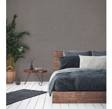 Schlafzimmer mit Holzbett, Nachttisch, Zimmerpflanze und Teppich auf Holzboden.