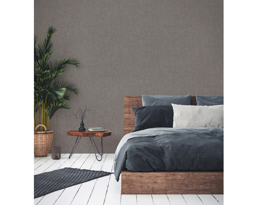 Schlafzimmer mit Holzbett, Nachttisch, Zimmerpflanze und Teppich auf Holzboden.