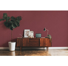 Pièce avec commode, lampe de table, ordinateur portable et plante d''intérieur devant un mur rouge