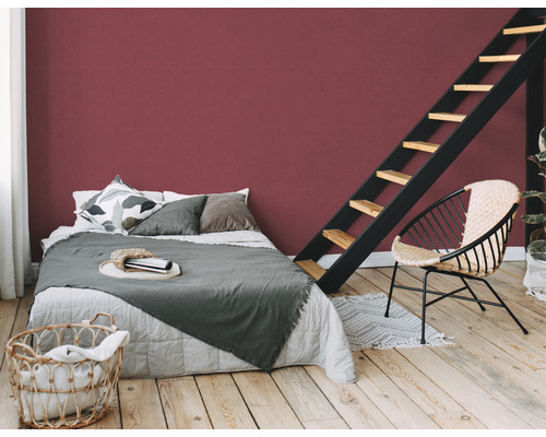 Chambre avec lit, échelle, chaise et mur rouge