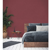 Chambre avec lit, table de chevet, plante d''intérieur et tapis sur plancher en bois devant un mur coloré