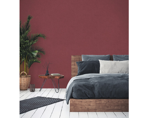 Chambre avec lit, table de chevet, plante d''intérieur et tapis sur plancher en bois devant un mur coloré