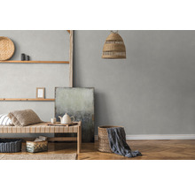 Helles Zimmer mit Rattanlampe, Wandregal und grauer Tapete