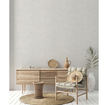 Heller Raum mit Holzkommode, Stuhl mit Hut, rundem Teppich und Dekorationen für ein gemütliches Ambiente