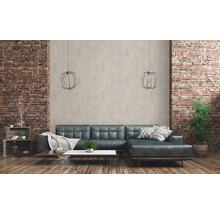 Wohnzimmer mit Ledersofa, Couchtisch, Regalen und dekorativen Elementen vor einer Backsteinwand
