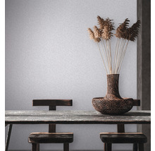 Scène avec table, chaises, vase et décoration devant un papier peint mural clair.