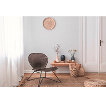 Salon avec fauteuil en rotin, table et décorations sur un tapis en fibres naturelles