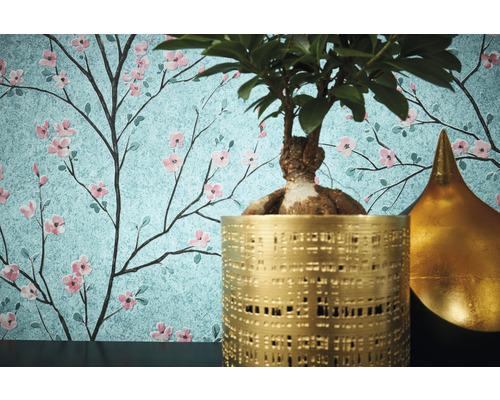 Dekorative Tapete mit floralem Kirschblütenmuster, kombiniert mit Topfpflanze und goldfarbener Dekoration.