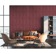 Wohnzimmer mit braunem Ledersofa, Sessel und einer Wand mit geometrischer Tapete