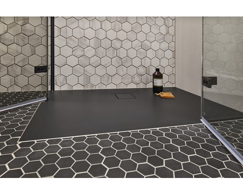 Douche plain-pied avec receveur noir et carrelage hexagonal au mur et au sol.