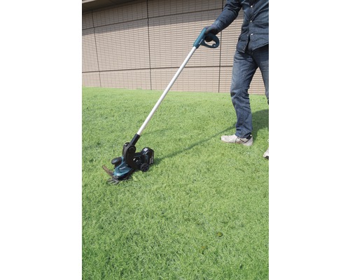 Person verwendet Akku-Rasenkantenschneider im Garten.
