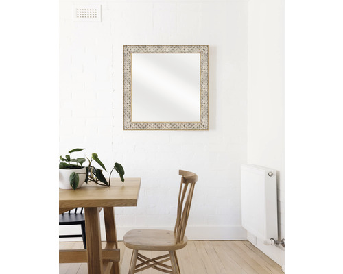 Dekorativer Spiegel mit Holzrahmen über einem Esstisch an einer Wand.