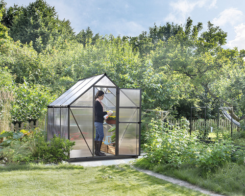 Gewächshaus mit geöffneter Tür und einer Person, die eine Pflanze pflegt, im Garten