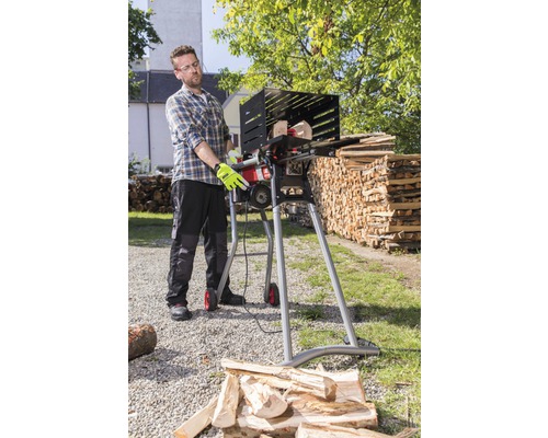 Un homme utilise une scie à bois de chauffage pour couper du bois à l''extérieur.