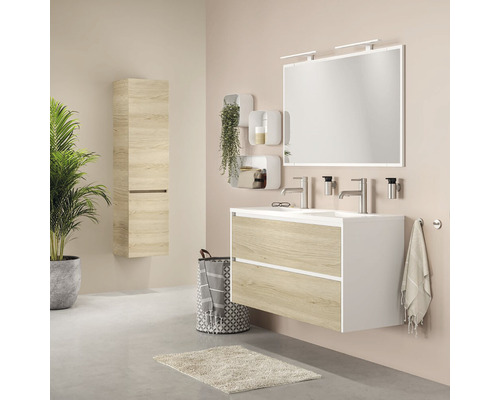 Salle de bains avec lavabo, miroir, armoire suspendue et décorations pour une ambiance claire et conviviale.