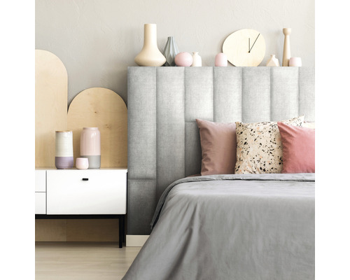 Chambre avec tête de lit rembourrée, linge de lit et éléments décoratifs.