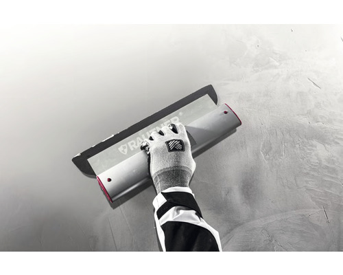 Artisan utilisant une lisseuse pour enduire un mur