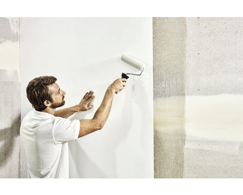 Ein Mann tapeziert eine Wand mit einer Farbwalze.