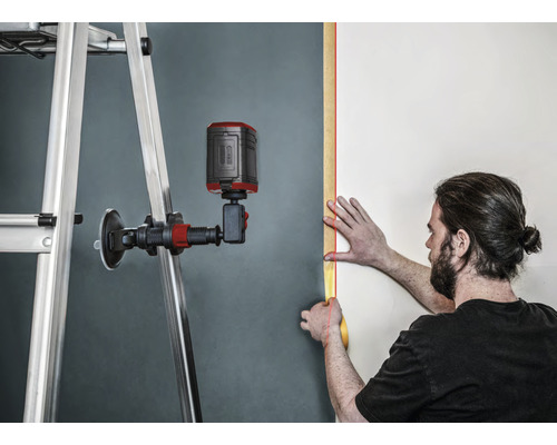 Utilisateur avec un laser linéaire alignant sur un mur avec une échelle