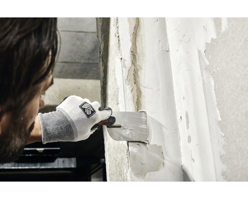 Un homme enduit un mur avec un enduit.