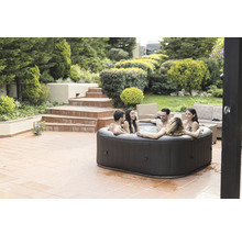 Jacuzzi gonflable dans le jardin avec des personnes qui se détendent.