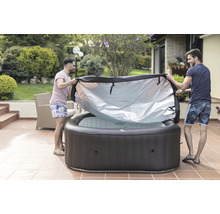 Deux hommes retirent la couverture d''un jacuzzi gonflable dans le jardin.