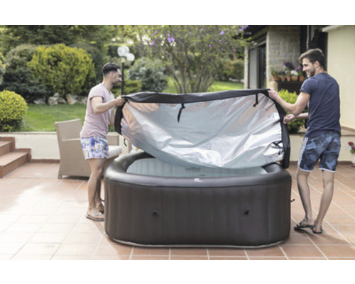 Deux hommes retirent la couverture d''un jacuzzi gonflable dans le jardin.